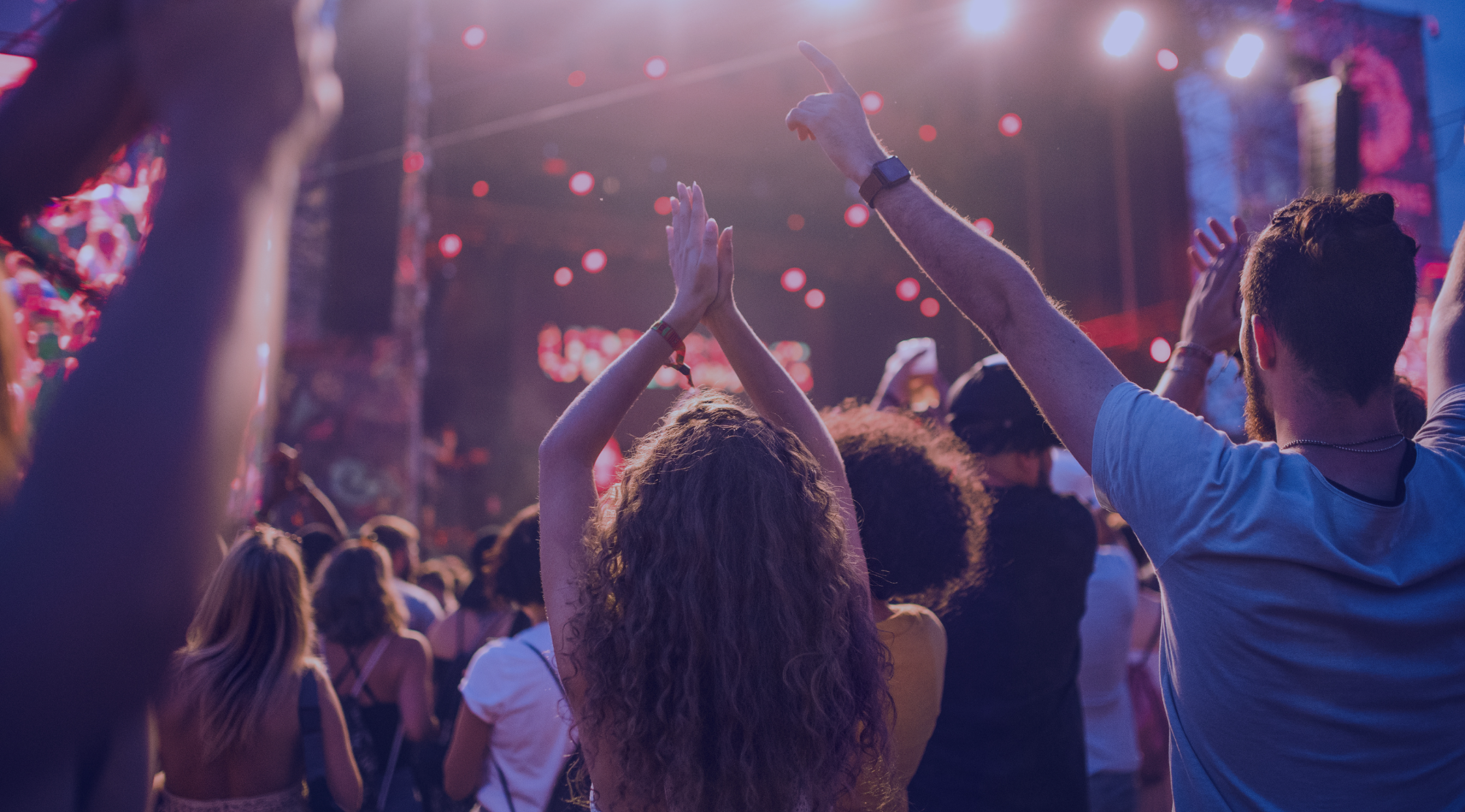 Besucher feiern vor einer beleuchteten Festivalbühne und genießen die Stimmung eines Live-Konzerts mit Musik, Lichteffekten und einer begeisterten Crowd.