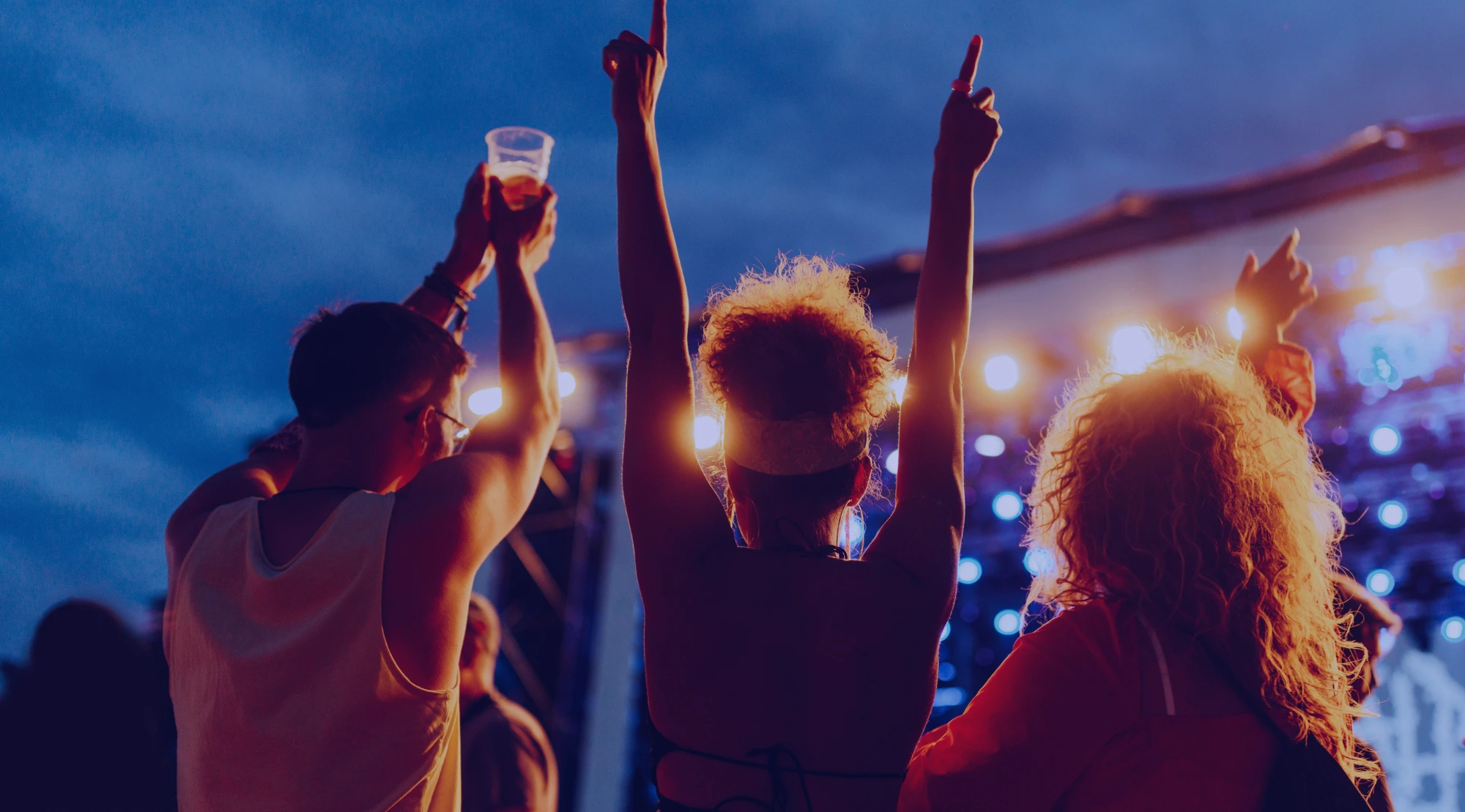 Festivalbesucher feiern gemeinsam vor einer beleuchteten Konzertbühne.