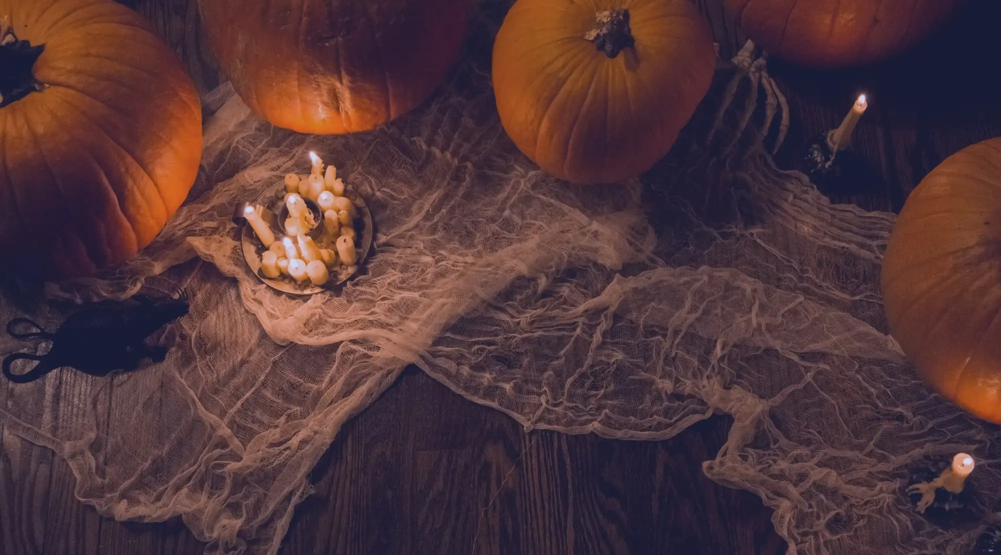 Halloween-Dekoration mit Kürbissen, Spinnennetz und Kerzen.