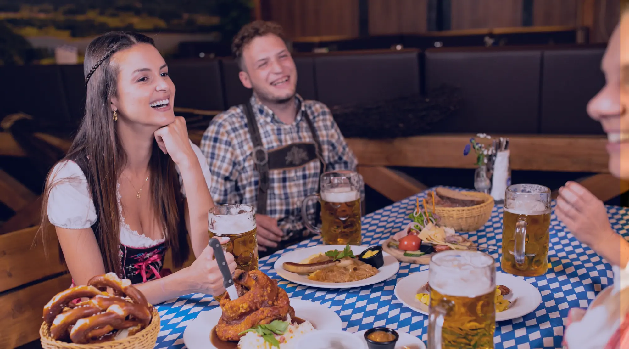 Gäste feiern gemeinsam bei Bier und Essen auf einem Oktoberfest.