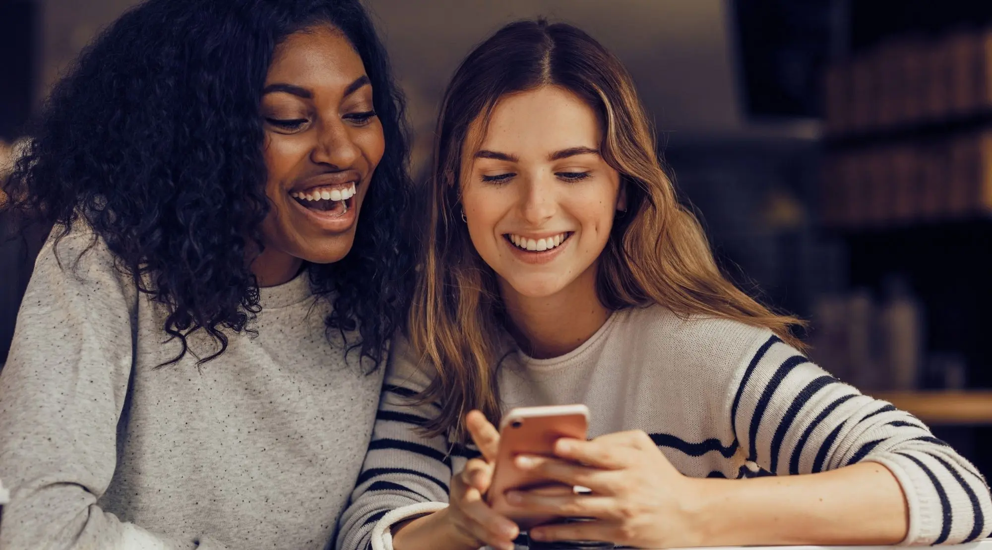 Zwei Freundinnen schauen gemeinsam auf ein Smartphone.